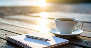 ノートとペン、コーヒーカップのあるテーブル